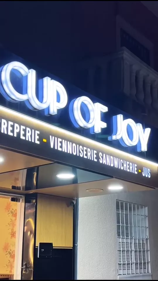 The lit Cup of Joy storefront sign at night