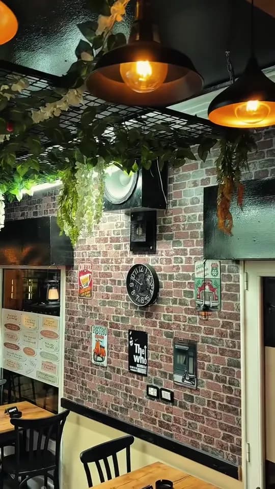 Brick wall, hanging plants and warm lamps inside a coffee shop